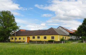 Biohof Weißensteiner, © Wolfgang Weißensteiner Gelbes Bauernhaus auf einer grünen Wiese mit blauem Himmel und Wolken.