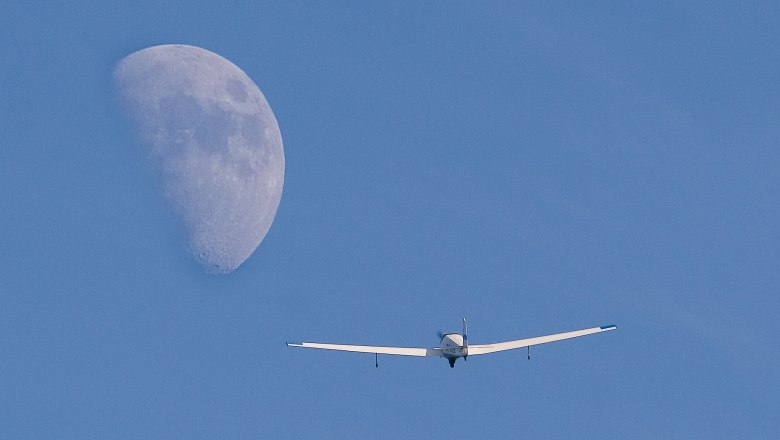 Flugplatz Ottenschlag03, © Union Segelfliegergruppe Ottenschlag Ein Segelflugzeug fliegt vor einem großen Mond am blauen Himmel.