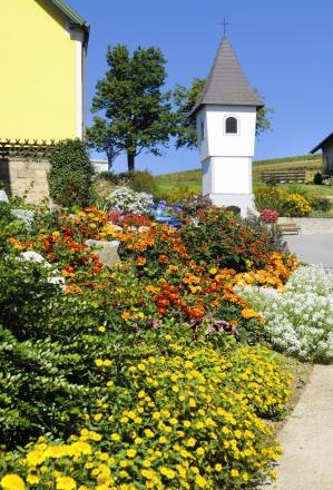 Blumendorf Ebergersch, © Gemeinde Lichtenau Ein blühender Garten mit bunten Blumen vor einem kleinen, weißen Kapellengebäude.