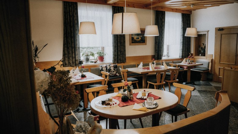 Beautiful parlor, large guest garden with walnut trees, © Niederösterreich Werbung/Rita Newman Cozy dining room with wooden furniture, set tables and hanging lamps.