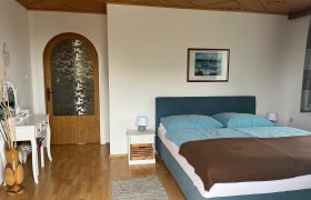 Schlafzimmer, © Ferienwohnung Meindl-Grübling Schlafzimmer mit Doppelbett, Kommode und Holztür.