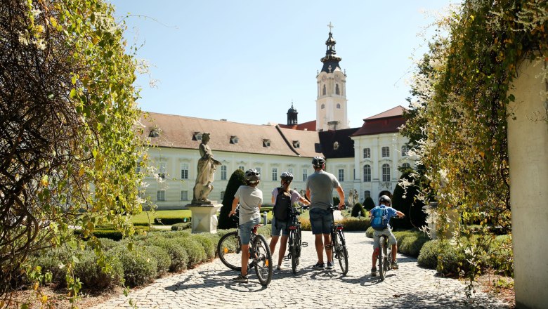 Kamp-Thaya-March Radroute, © Waldviertel Tourismus, Studio Kerschbaum Familie mit Fahrrädern vor einem historischen Gebäude mit Turm.