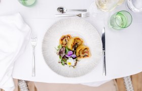 Gefüllte Erdäpfelroulade, © Niederösterreich Werbung/Mara Hohla Ein Teller mit gefüllter Erdäpfelroulade und Salat auf einem gedeckten Tisch.