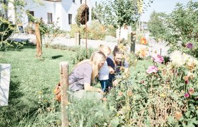 Familienausflug, © ©SONNENTOR/@nudlholz.at Familie betrachtet Blumen im Garten.