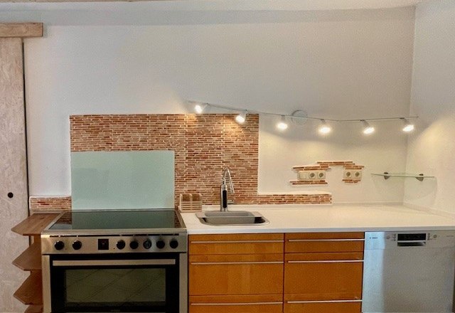 Kitchen, © Julia Grünschachner Modern kitchen with stove, sink and dishwasher in front of a mosaic tiled wall.