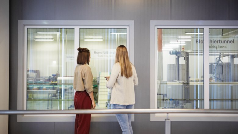 Schaugang, © Waldviertel Tourismus, Gerhard Wasserbauer Zwei Frauen betrachten durch ein Fenster eine Produktionsanlage.
