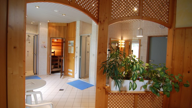Wohlfühl-Oase, © Gasthof Nordwald Innenansicht eines Wellnessbereichs mit Sauna, Pflanzen und Sitzbereich.