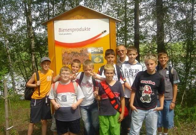 Bienenlandl 2, © Robert Schmutz Gruppe von Jungen vor einem Schild mit der Aufschrift 'Bienenprodukte' im Freien.