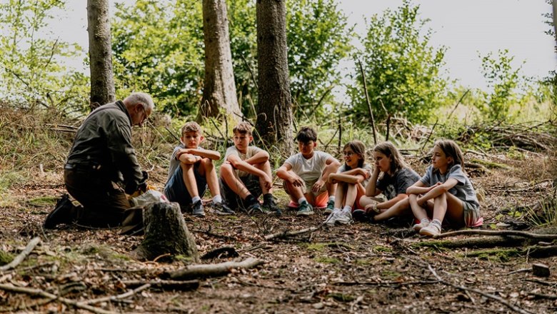 Waldschule Waldviertel, © Waldviertel Tourismus, Matthias Streibel Ein älterer Mann spricht zu einer Gruppe von Kindern im Wald.