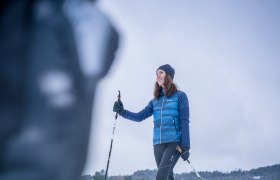 Langlaufen in St. Oswald, © Waldviertel Tourismus, Robert Herbst Eine Frau beim Langlaufen auf einer schneebedeckten Fläche mit Häusern im Hintergrund.