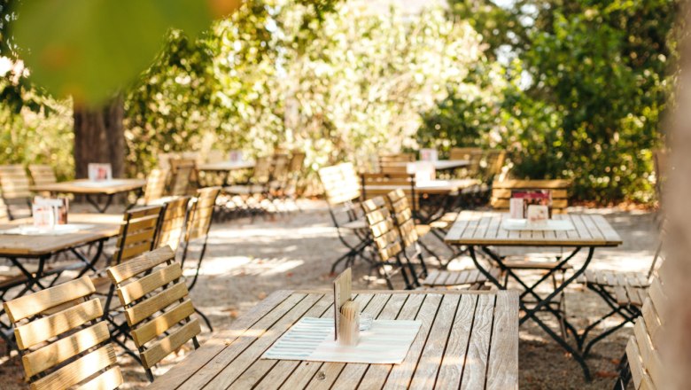Idyllischer Gastgarten mit alten Kastanienbäumen, © Niederösterreich Werbung / Daniela Führer Ein Gastgarten mit Holztischen und -stühlen unter Kastanienbäumen.