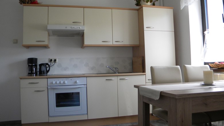 Küche mit Essecke, © vera.s Moderne Küche mit cremefarbenen Schränken, Esstisch und Stühlen.