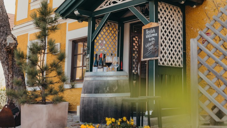 Inn in Austria's first lazy hotel, © Niederösterreich Werbung/Daniela Führer Entrance of a pub with wine barrel, glasses and flowers.