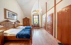 StiftAltenburg_Doppelzimmer, © Martin Mathes Ein elegantes Doppelzimmer mit antiken Holzmöbeln, einem Kronleuchter und einem Fenster mit Blick ins Grüne.