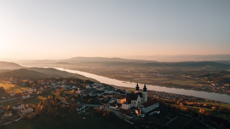 Place of pilgrimage Maria Taferl, © Niederösterreich Werbung/thecreatingclick.com Aerial view of a church at sunset, surrounded by river and landscape.