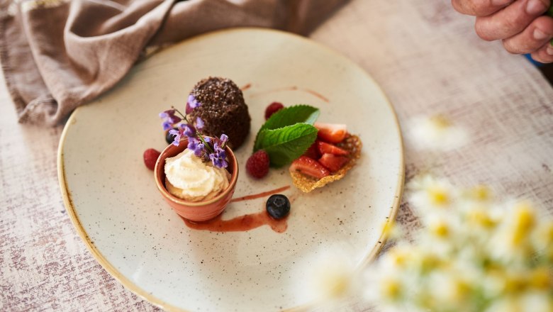 Bio-Gasthaus Leibspeis', © SONNENTOR/ @nudlholz.at Ein Dessertteller mit verschiedenen Süßspeisen, dekoriert mit Blumen und Beeren.