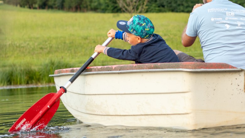 Boot fahren am Teich, © Familie Moser Ein Kind und ein Erwachsener rudern in einem kleinen Boot auf einem Teich.