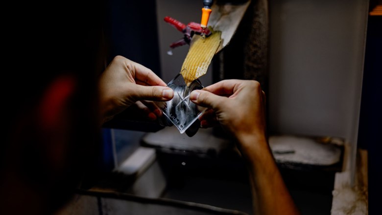 KRISTALLIUM glas.erleben., © Waldviertel Tourismus, Matthias Streibel Nahaufnahme von Händen, die ein Glasstück an einer Schleifmaschine bearbeiten.