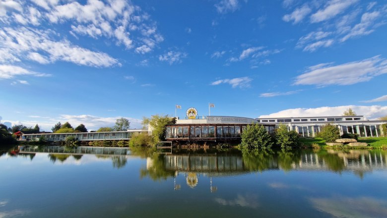 Exterior view of the cheese-making world, © Käsemacherwelt Exterior view of the cheese maker's world with blue sky and lake in the foreground.