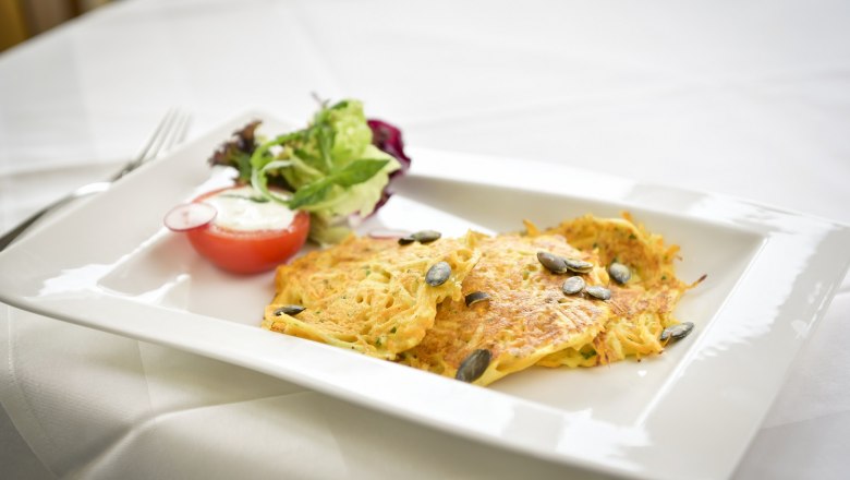 Healthy indulgence, © Moorheilbad Harbach A plate of potato pancakes, pumpkin seeds and salad on a white table.