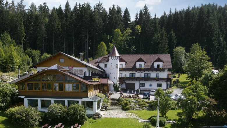 Märchenhotel Waldpension Nebelstein, © Andreas Schmidt Ein Hotel im Wald mit einem Turm und Garten.