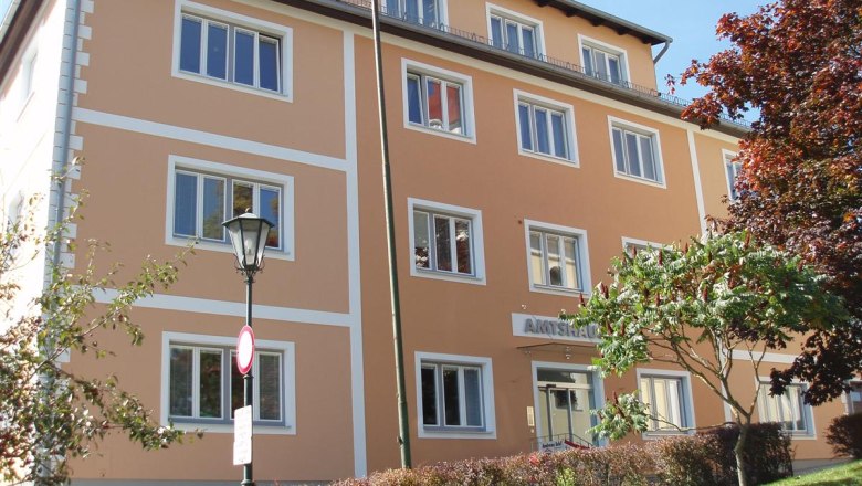 Tourismusinformation Lichtenau, © Tourismusinformation Lichtenau Ein dreistöckiges, orangefarbenes Gebäude mit weißen Fensterrahmen und einem Schild mit der Aufschrift 'Amtshaus'.