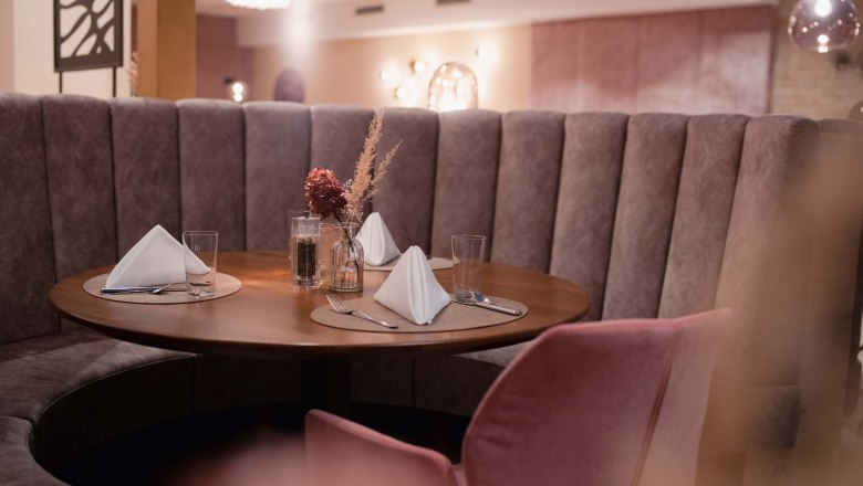 Restaurant Wintergarten Detail Hotel Schachner, © Hotel Schachner_MIKU Media Elegantes Restaurant mit runder Sitzbank und gedecktem Tisch.