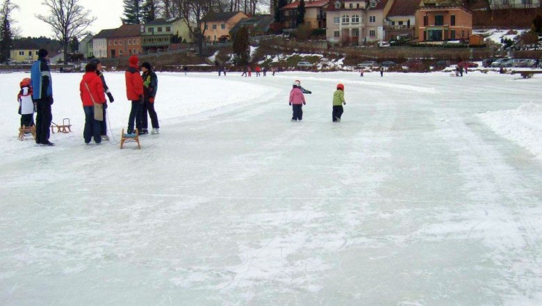 Ice skating at the Allentsteig town lake, © Waldhör People skating on a frozen lake in Allentsteig, surrounded by houses and trees.