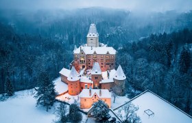 Schloss Ottenstein, © Niederösterreich Werbung, Robert Herbst Luftaufnahme von Schloss Ottenstein im Winter, umgeben von schneebedeckten Bäumen und beleuchtetem Innenhof.