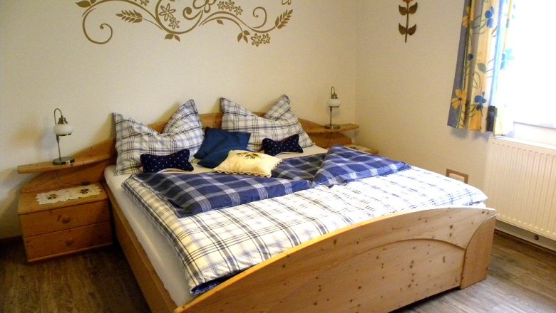 Rooms Guesthouse Zur alten Buche, © Fam. Dörr Cozy bedroom with wooden bed and blue bed linen.