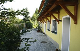 Binder Hof, © Familie Binder Gepflasterter Hof mit gelbem Gebäude und Gartenmöbeln.