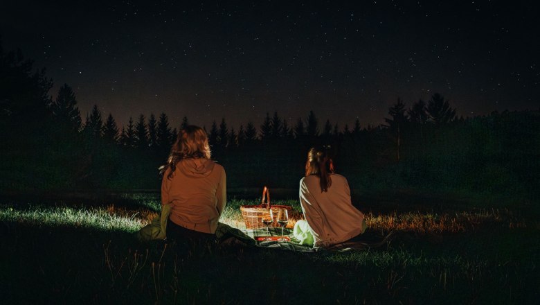 Sterne schauen im Waldviertel, © Waldviertel Tourismus, Line Sulzbacher Zwei Personen sitzen nachts auf einer Wiese und schauen in den Sternenhimmel.