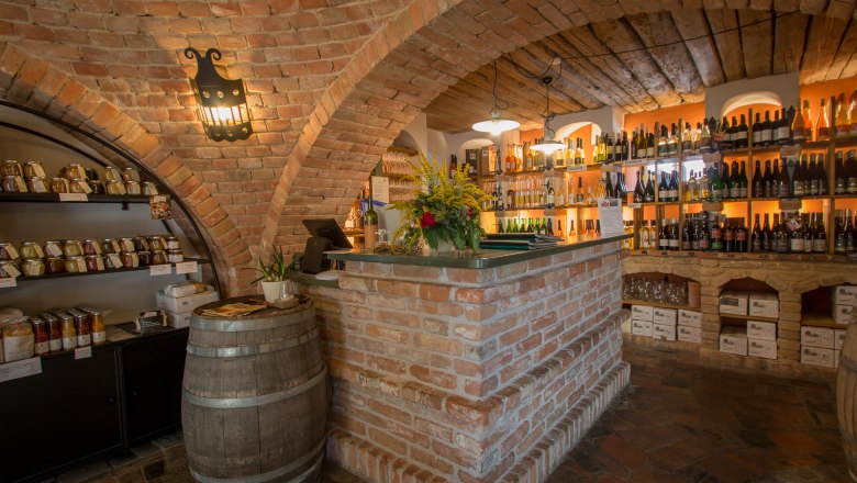 The bar, © Alte Schmiede Schönberg Cozy wine bar with brick walls, shelves full of wine bottles and a rustic counter.