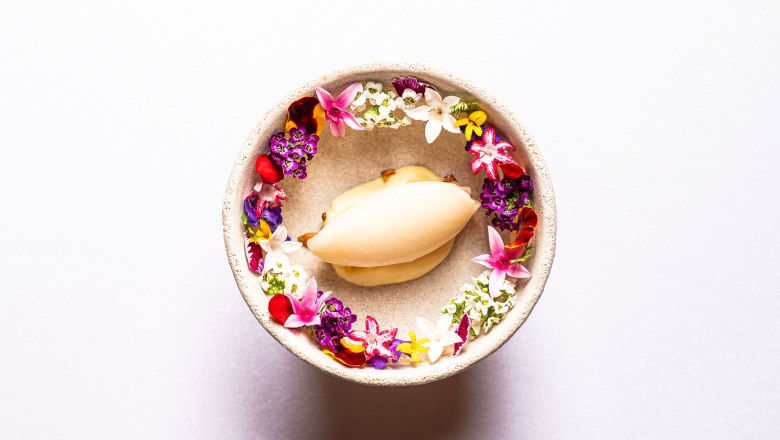 Tarte Tatin, © Claus Kadrnoschka Ein Dessert in einer Schale, umgeben von bunten essbaren Blüten.