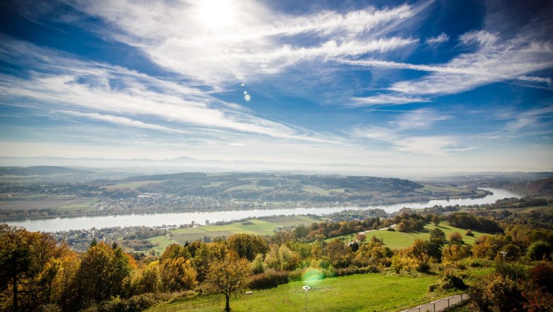 Aussicht vom Hotel Schachner, © Hotel Schachner Panoramablick auf eine Flusslandschaft mit grünen Feldern und blauem Himmel.
