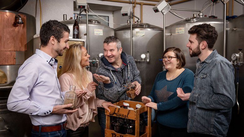 Wirtshausbrauerei Haselböck, © Waldviertel Tourismus, Studio Kerschbaum Gruppe von Menschen in einer Brauerei mit Bierflaschen und Zutaten.