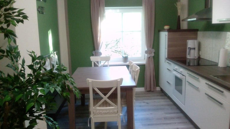 Kitchen, © Zimml Modern kitchen with green and white walls, dining table, chairs and kitchen appliances.