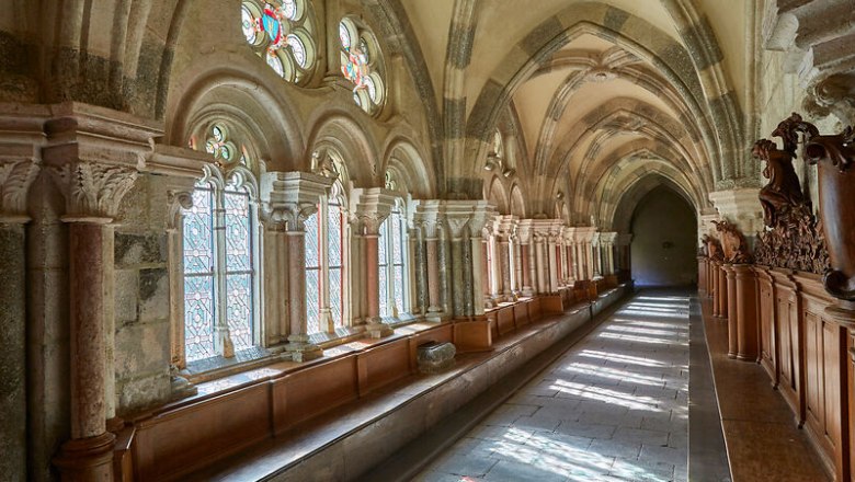 Kreuzgang, © Waldviertel Tourismus, lichtstark.com Ein historischer Kreuzgang mit gotischen Bögen und bunten Glasfenstern, durch die Sonnenlicht fällt.