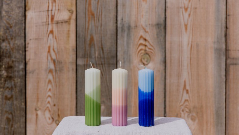 cooking candles, © Waldviertel Tourismus, Matthias Streibel Three colorful candles on a table in front of a wooden wall.