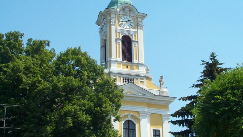 Stadtgemeinde Groß-Siegharts, © Stadtgemeinde Groß-Siegharts Gelbe Kirche mit Turm und Uhr in Groß-Siegharts, umgeben von Bäumen.