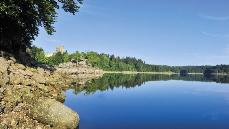 Kampsee Ottenstein, © Waldviertel Tourismus Kampsee Ottenstein mit ruhigem Wasser, bewaldeten Ufern und einer Burg im Hintergrund.