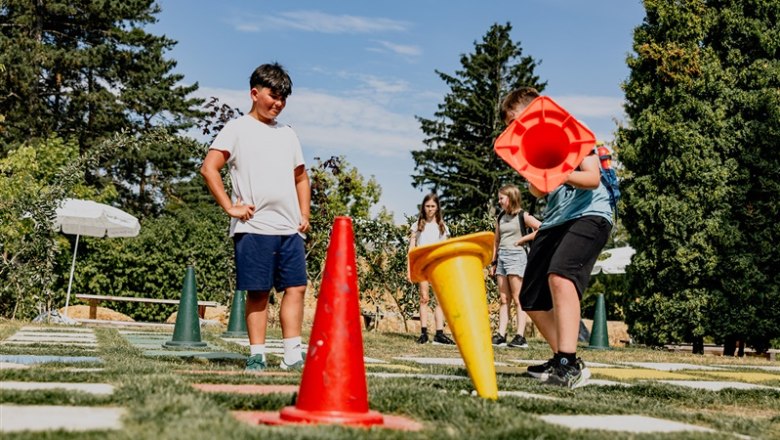 Kittenberg adventure gardens, © Matthias Streibel Children play outdoors with large colorful cones on a grass field.