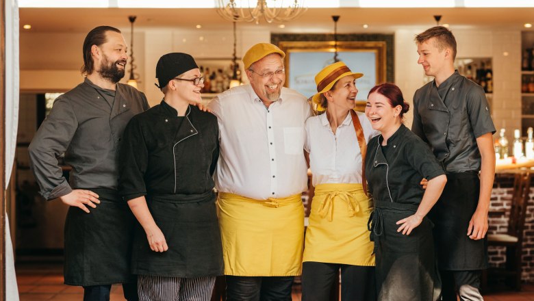 Das motivierte Team vom Schlossgasthof, © Niederösterreich Werbung / Daniela Führer Ein fröhliches Team von sechs Personen in Arbeitskleidung steht lächelnd in einem Restaurant.