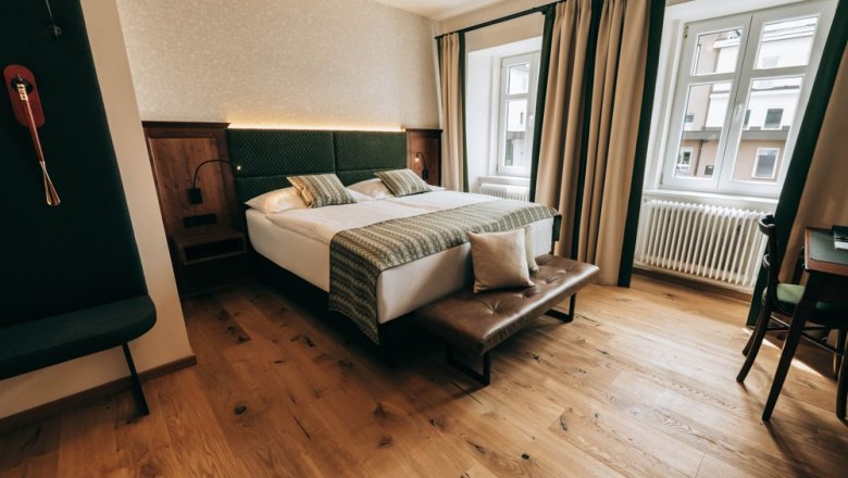 Zum Goldenen Löwen, © Zum Goldenen Löwen Gemütliches Hotelzimmer mit Doppelbett, Holzboden und großen Fenstern.