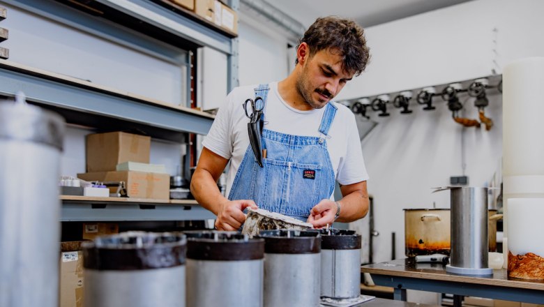 koch-kerzen, © Waldviertel Tourismus, Matthias Streibel Mann in Latzhose arbeitet in einer Werkstatt mit Kerzenformen.