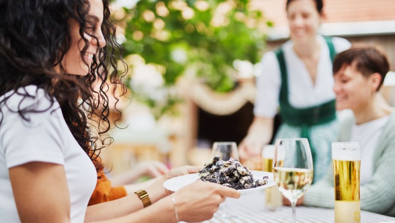 Mohnwirt Neuwiesinger, © Waldviertel Tourismus, Gerhard Wasserbauer Personen genießen Essen und Getränke im Freien an einem Tisch.