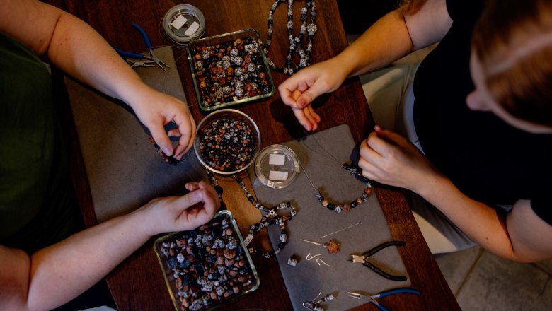 Granitschmuck fertigen, © Waldviertel Tourismus, Matthias Streibel Zwei Personen fertigen Granitschmuck an einem Tisch mit Perlen und Werkzeugen.
