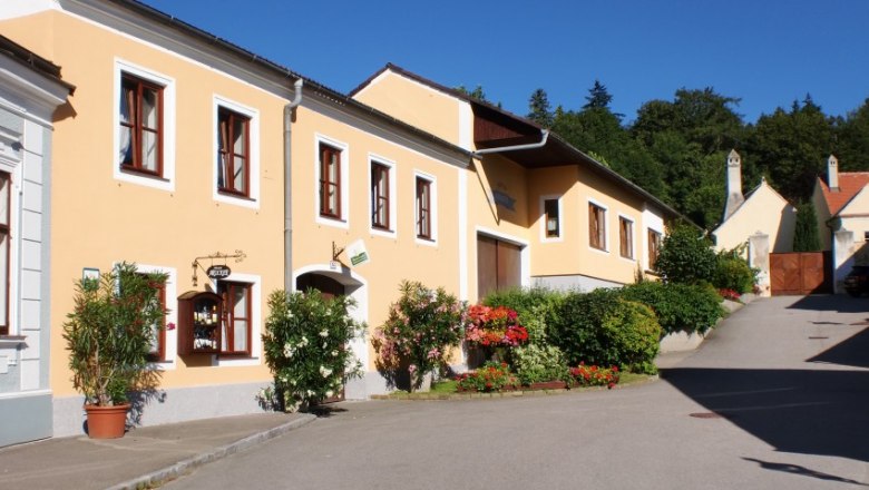 Haus, © Familie Arocker Gelbes Haus mit Blumen und blauen Himmel im Hintergrund.
