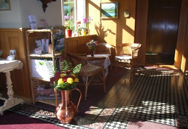 Entrance hall Waldpension, © Barbara Mück Entrance hall of a guesthouse with wicker furniture, flowers and decorative floor pattern.