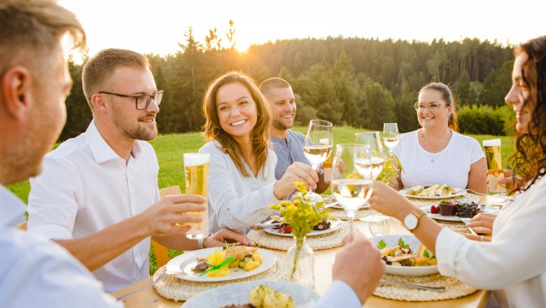 Genussreise durchs Waldviertel, © Waldviertel Tourismus, Doris Schwarz-König Menschen stoßen bei einem Essen im Freien an, umgeben von Natur.
